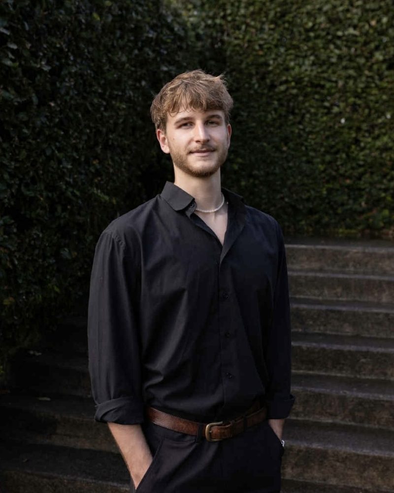 Seb, founder of Dropped Pin, standing in front of a hedge and stone steps
